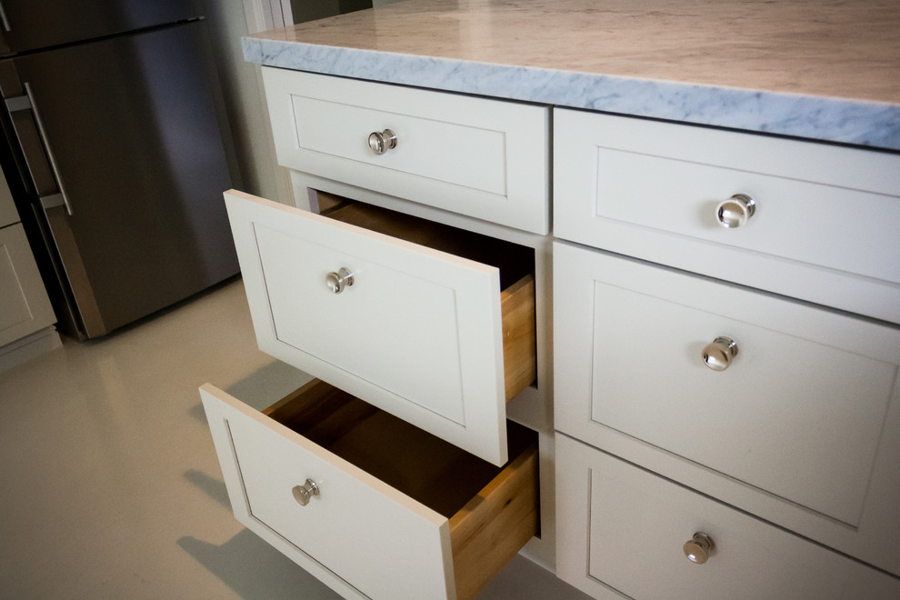 Example of a transitional kitchen design in San Francisco with a farmhouse sink, white cabinets and marble countertops