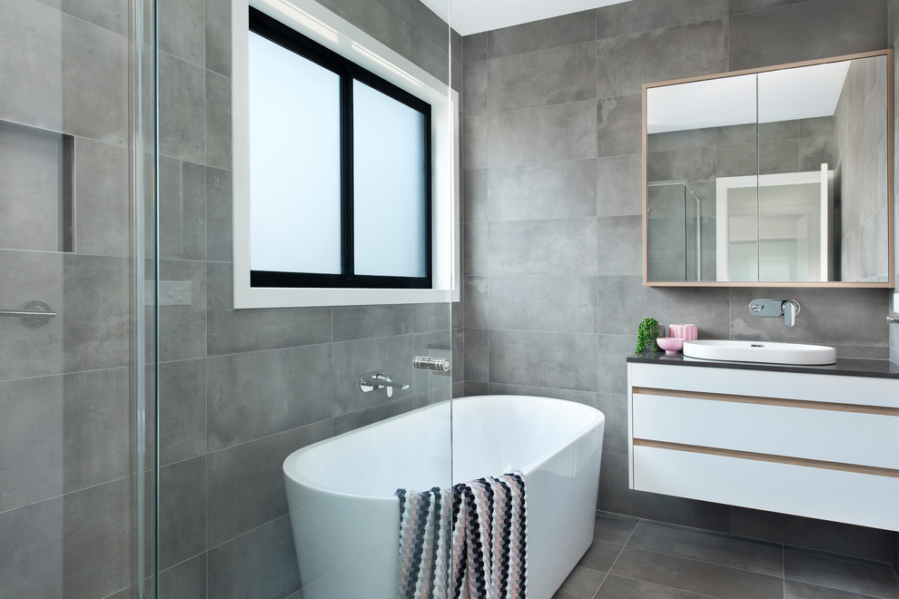 Inspiration for a contemporary bathroom in Canberra - Queanbeyan with flat-panel cabinets, white cabinets, a freestanding tub, gray tile, a drop-in sink, grey floor and grey benchtops.