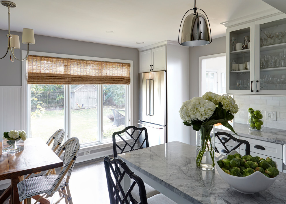 Kitchen - transitional medium tone wood floor kitchen idea in Chicago with a farmhouse sink, white cabinets, quartzite countertops, white backsplash, stone tile backsplash, stainless steel appliances and an island