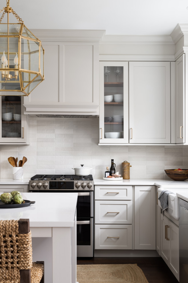 Inspiration for a medium sized traditional u-shaped kitchen/diner in DC Metro with a belfast sink, shaker cabinets, grey cabinets, engineered stone countertops, grey splashback, ceramic splashback, stainless steel appliances, dark hardwood flooring, an island, brown floors and white worktops.