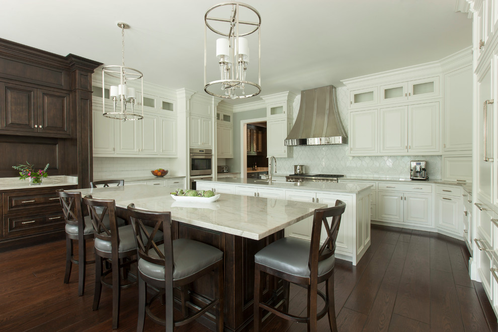 Design ideas for a traditional kitchen in Chicago with raised-panel cabinets, white cabinets, white splashback, stainless steel appliances, dark hardwood floors, multiple islands, brown floor and quartzite benchtops.