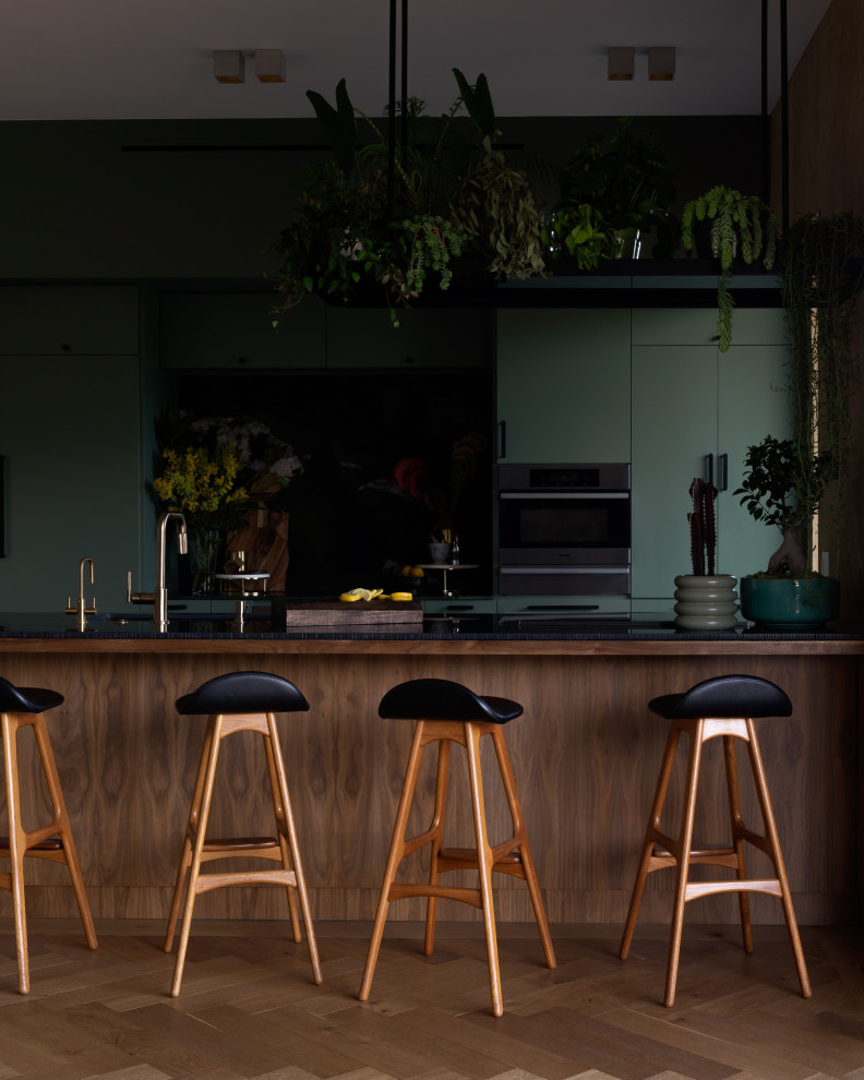 Свежая идея для дизайна: параллельная кухня среднего размера в стиле модернизм с полуостровом, обеденным столом, врезной мойкой, плоскими фасадами, зелеными фасадами, столешницей из кварцита, зеленым фартуком, фартуком из гранита, техникой из нержавеющей стали, полом из известняка, бежевым полом, черной столешницей и балками на потолке - отличное фото интерьера