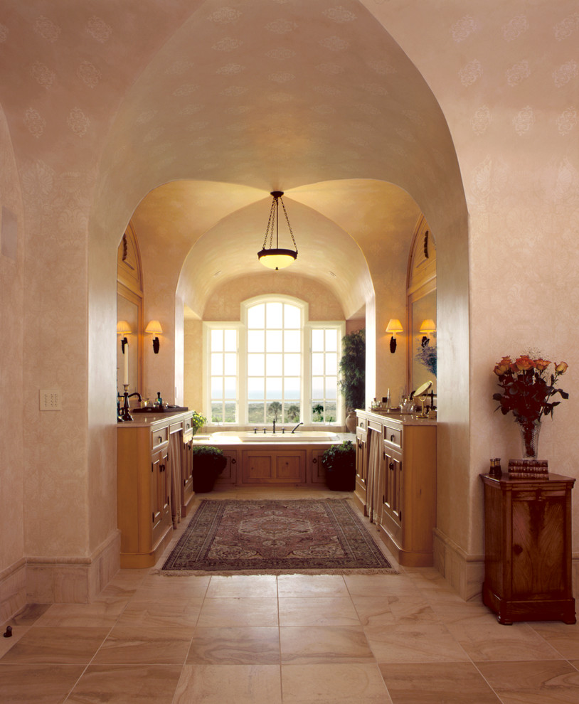 Inspiration for a large traditional master bathroom in Charleston with recessed-panel cabinets, medium wood cabinets, a drop-in tub, beige tile, stone tile, beige walls, travertine floors, an undermount sink and marble benchtops.