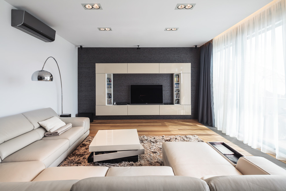 This is an example of a large contemporary family room in Other with grey walls, light hardwood floors and a built-in media wall.