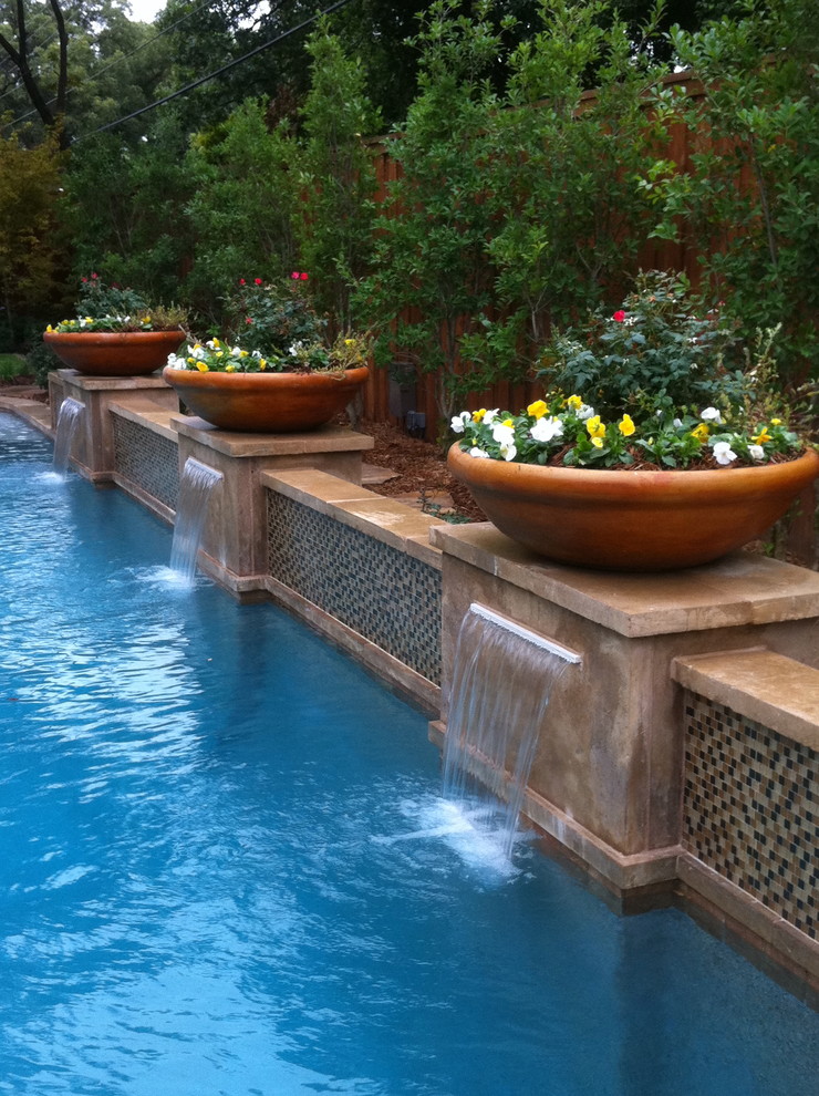 Large contemporary backyard custom-shaped pool in Dallas with a water feature.