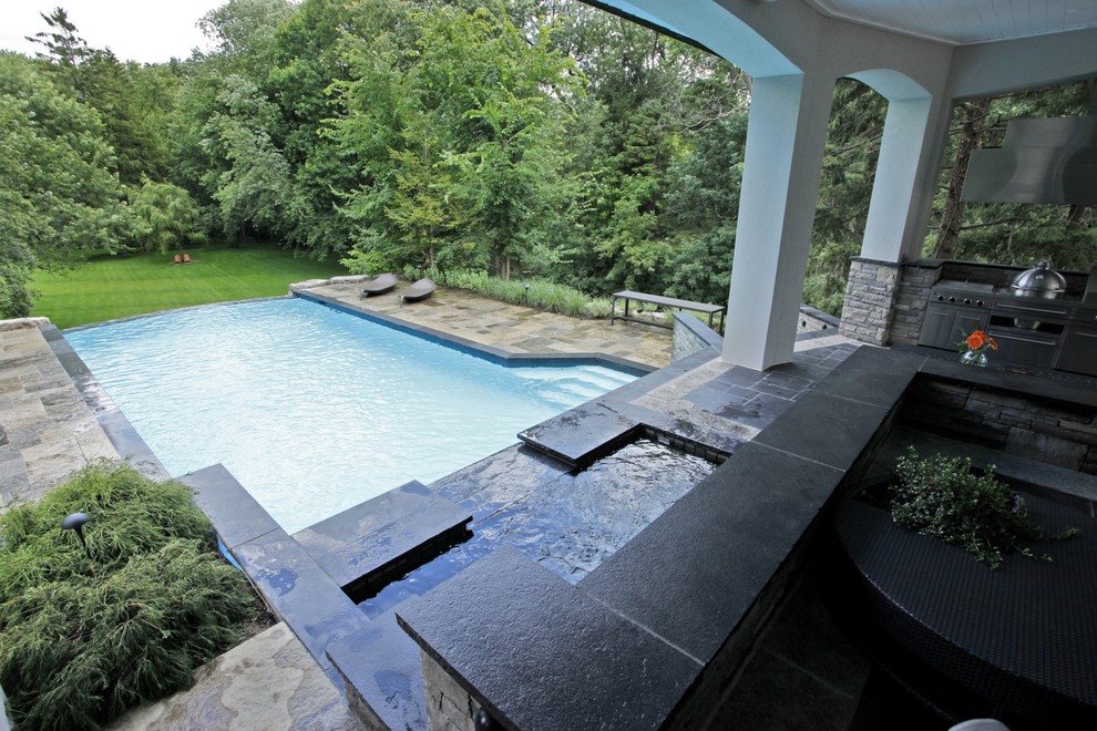 Large trendy backyard stone and rectangular infinity hot tub photo