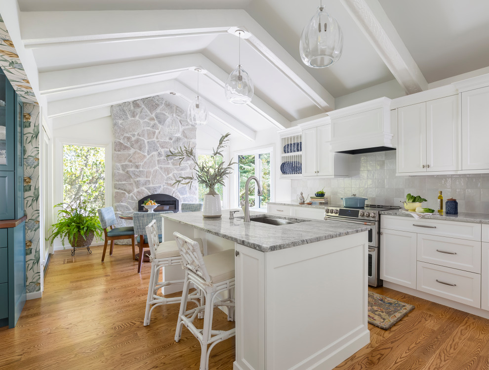 Foto på ett mellanstort vintage grå linjärt kök och matrum, med en undermonterad diskho, luckor med infälld panel, vita skåp, granitbänkskiva, vitt stänkskydd, stänkskydd i keramik, integrerade vitvaror, mellanmörkt trägolv, en köksö och brunt golv