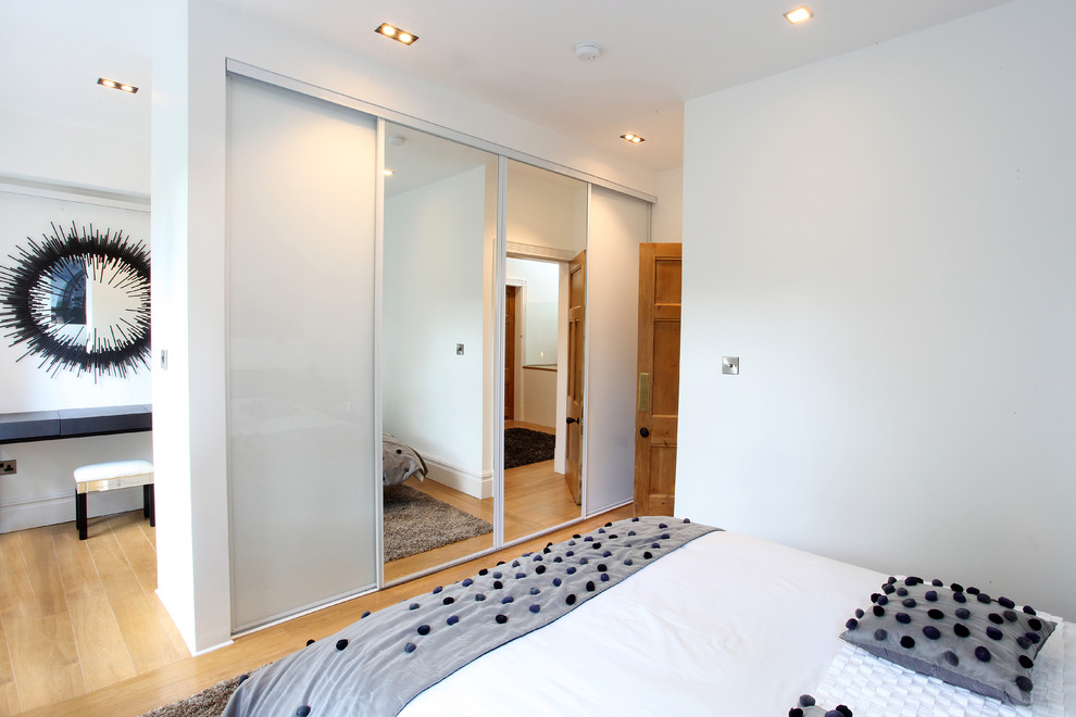 Mid-sized contemporary master bedroom in Manchester with white walls and light hardwood floors.
