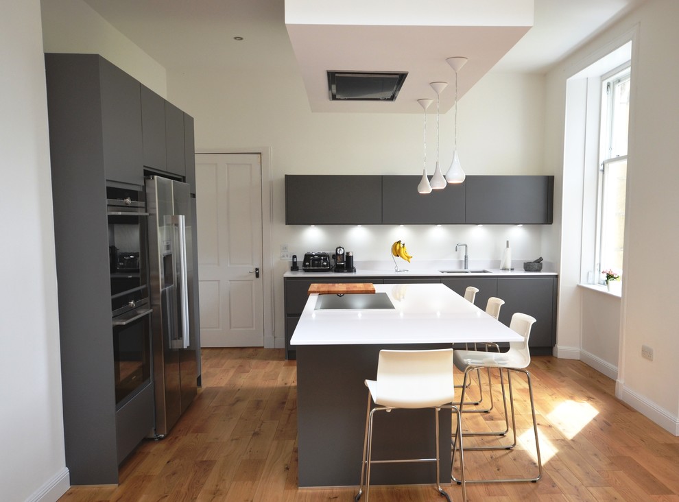 Photo of a mid-sized contemporary u-shaped eat-in kitchen in Glasgow with a double-bowl sink, flat-panel cabinets, grey cabinets, limestone benchtops, black splashback, marble splashback, black appliances, dark hardwood floors, with island and brown floor.