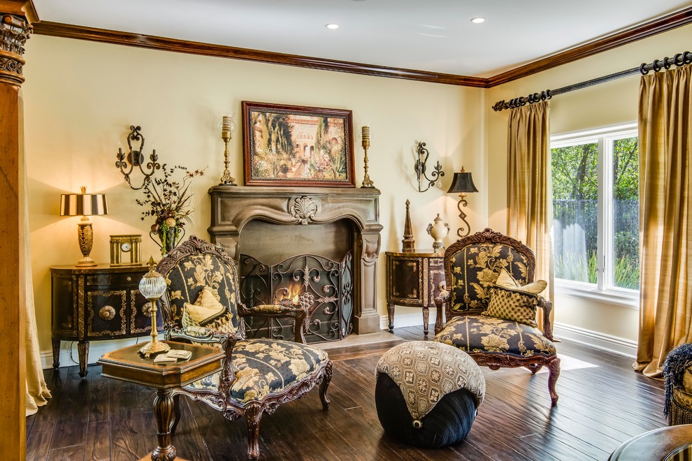 This is an example of a mid-sized mediterranean enclosed living room in Los Angeles with beige walls, medium hardwood floors, a standard fireplace, a concrete fireplace surround and no tv.