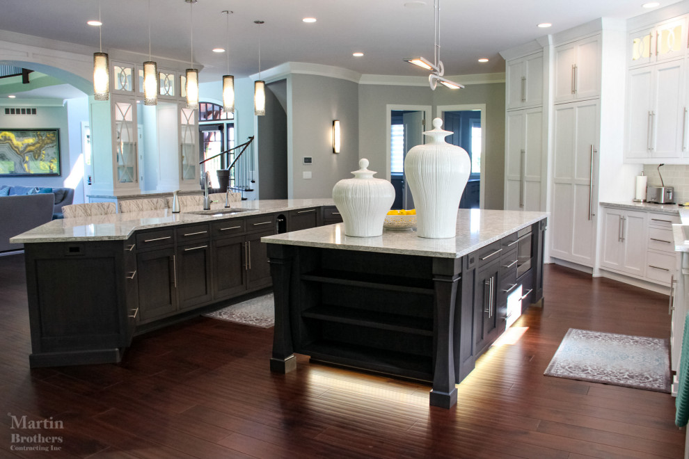 Huge transitional l-shaped dark wood floor kitchen pantry photo with an undermount sink, shaker cabinets, white cabinets, quartzite countertops, gray backsplash, ceramic backsplash, stainless steel appliances and two islands