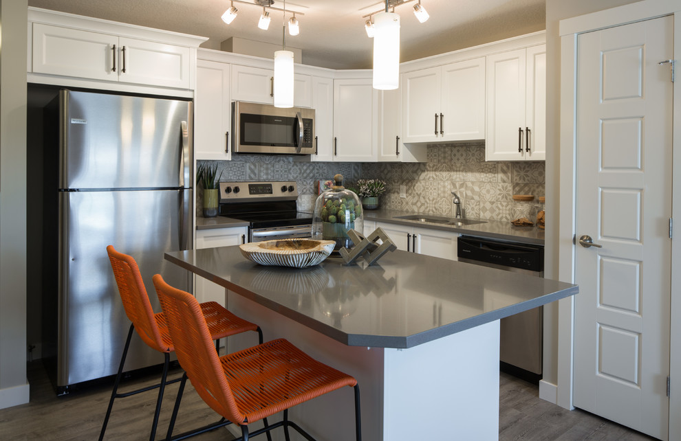 This is an example of a small eclectic l-shaped open plan kitchen in Calgary with shaker cabinets, white cabinets, quartz benchtops, with island and grey benchtop.