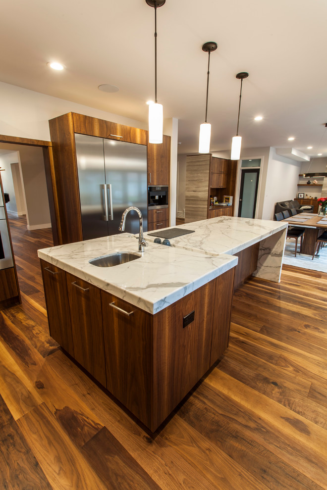 Photo of a large contemporary u-shaped open plan kitchen in Edmonton with a double-bowl sink, flat-panel cabinets, medium wood cabinets, marble benchtops, grey splashback, matchstick tile splashback, stainless steel appliances, medium hardwood floors and with island.