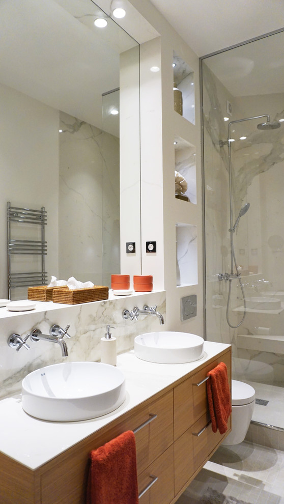 Inspiration for a contemporary bathroom in Paris with flat-panel cabinets, medium wood cabinets, a corner shower, a wall-mount toilet, white tile, white walls, mosaic tile floors, grey floor and white benchtops.