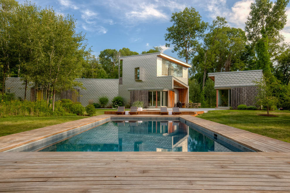 Inspiration for a large contemporary front yard custom-shaped pool in New York with a hot tub and decking.