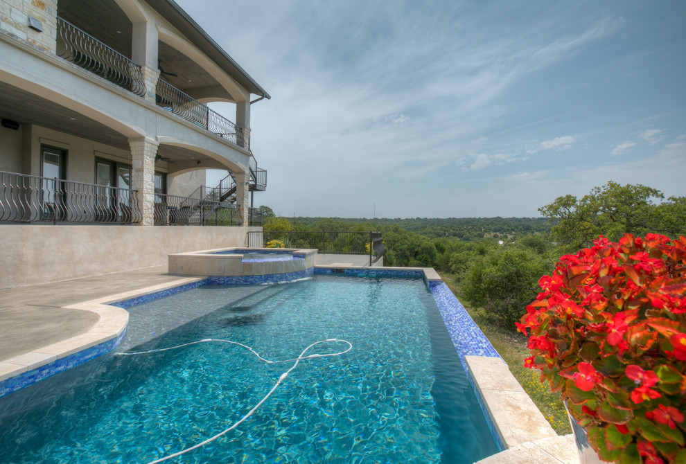 Design ideas for a large mediterranean backyard rectangular infinity pool in Austin with a hot tub and concrete slab.