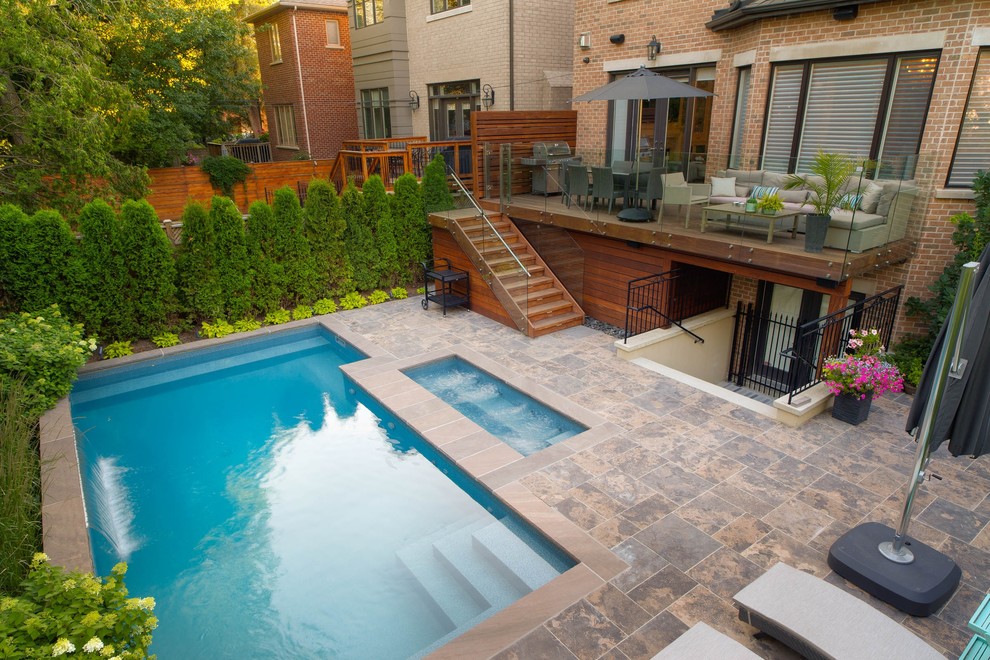 Photo of a small transitional backyard rectangular pool in Toronto with a hot tub and natural stone pavers.