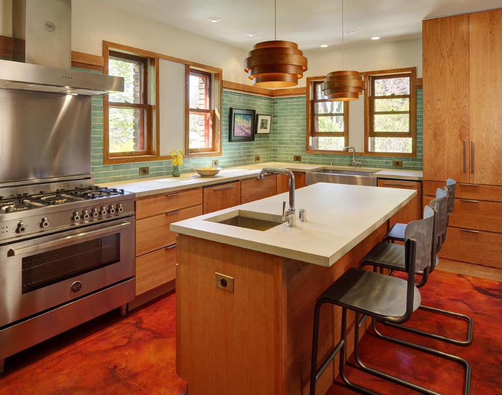 Design ideas for a mid-sized midcentury l-shaped eat-in kitchen in Milwaukee with a farmhouse sink, flat-panel cabinets, medium wood cabinets, green splashback, ceramic splashback, stainless steel appliances and with island.