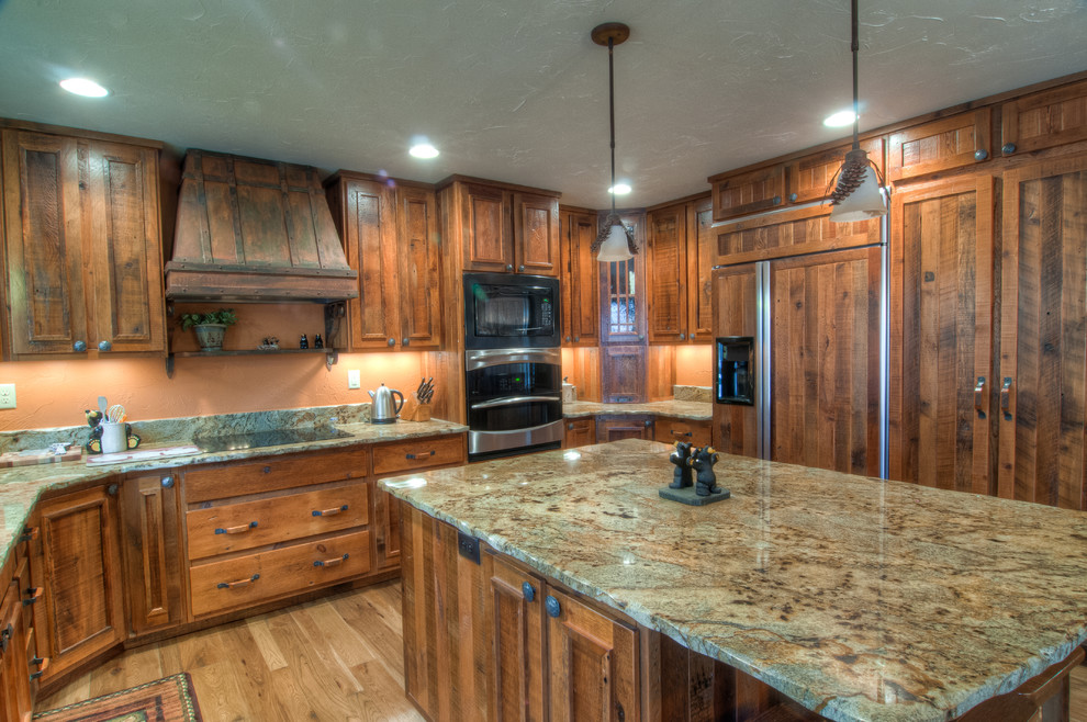 Mountain style u-shaped eat-in kitchen photo with an undermount sink, raised-panel cabinets, medium tone wood cabinets, granite countertops, beige backsplash and stainless steel appliances