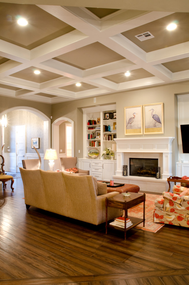 Photo of a large transitional open concept family room in Austin with beige walls, dark hardwood floors, a standard fireplace, a plaster fireplace surround and a wall-mounted tv.