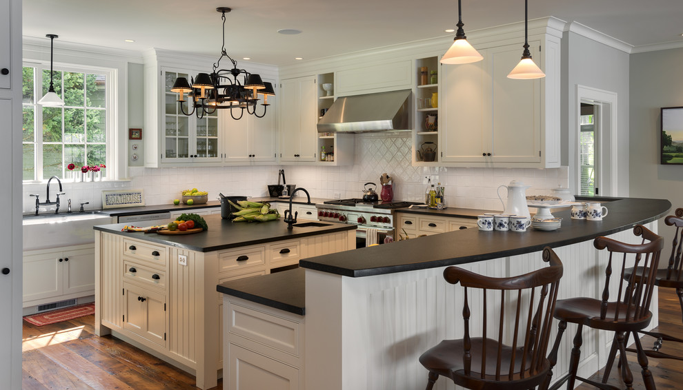 Traditional u-shaped kitchen in New York with a farmhouse sink, beaded inset cabinets, beige cabinets, white splashback and stainless steel appliances.