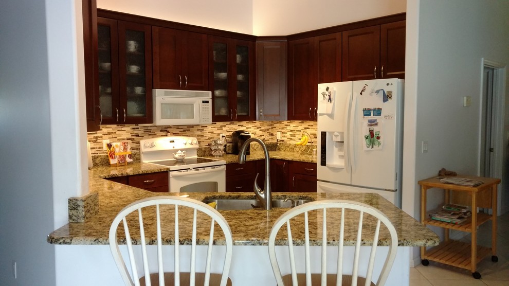 Small transitional u-shaped porcelain tile and beige floor kitchen photo in Miami with an undermount sink, shaker cabinets, dark wood cabinets, granite countertops, multicolored backsplash, glass tile backsplash, white appliances, a peninsula and multicolored countertops
