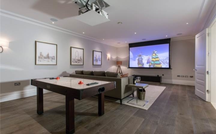 Design ideas for a mid-sized contemporary open concept family room in London with a game room, white walls, medium hardwood floors, no fireplace and a wall-mounted tv.