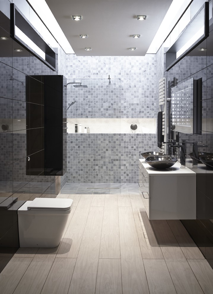 Large contemporary master bathroom in Hertfordshire with a vessel sink, flat-panel cabinets, black cabinets, a one-piece toilet, gray tile, mosaic tile, black walls, light hardwood floors and a curbless shower.