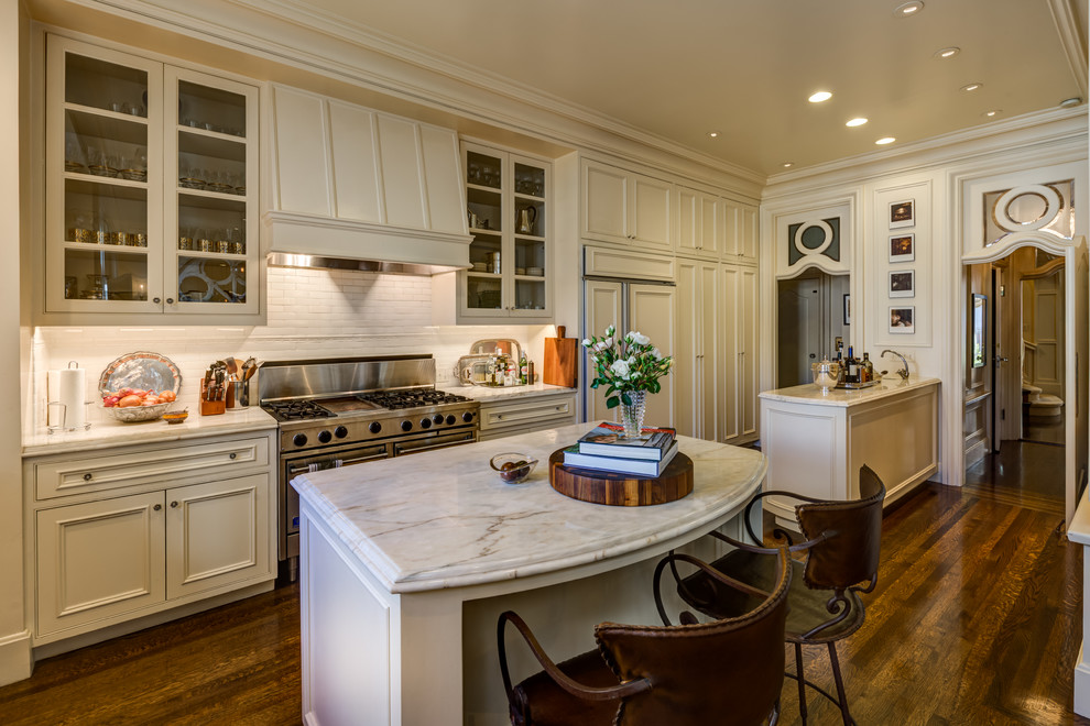 This is an example of a traditional galley kitchen in San Francisco with an undermount sink, beaded inset cabinets, white cabinets, marble benchtops, white splashback, subway tile splashback, panelled appliances, dark hardwood floors and with island.