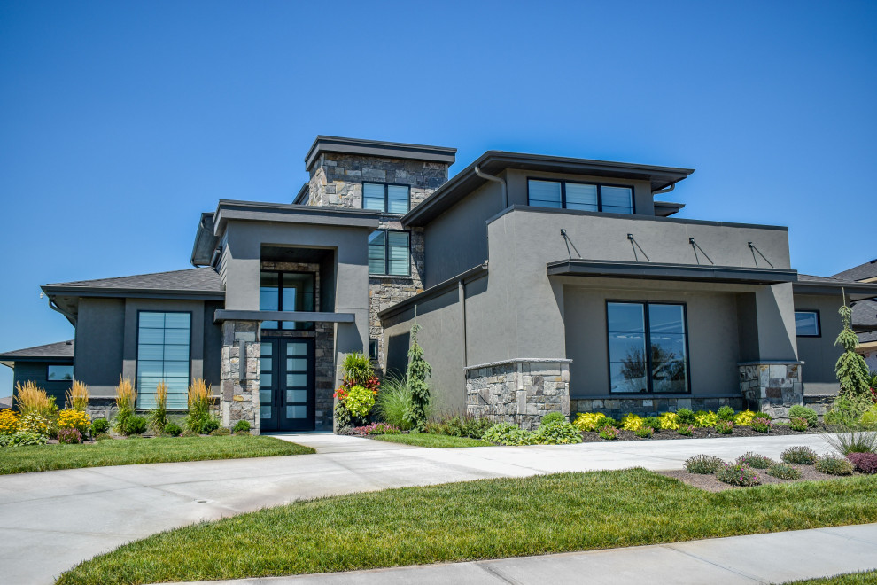This is an example of a modern black house exterior in Omaha with stone veneer, a shingle roof and a black roof.
