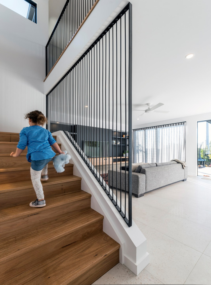 Photo of a contemporary wood u-shaped staircase with wood risers and metal railing.