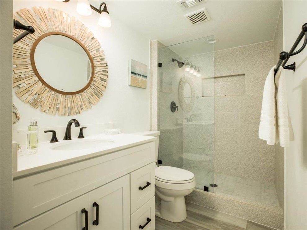 Inspiration for a mid-sized beach style 3/4 bathroom in Houston with shaker cabinets, white cabinets, an alcove shower, a two-piece toilet, white walls, porcelain floors, an undermount sink, beige floor, a hinged shower door and white benchtops.