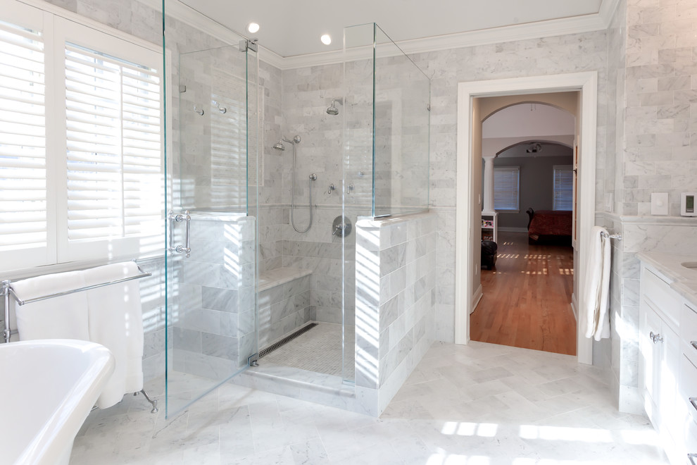 Large traditional master bathroom in New York with an undermount sink, white cabinets, marble benchtops, a freestanding tub, a corner shower, white tile, stone tile, grey walls, marble floors, beaded inset cabinets and a one-piece toilet.