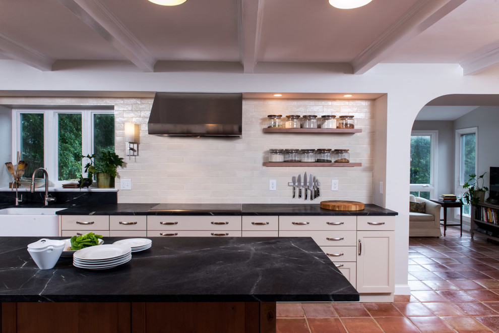 Transitional l-shaped eat-in kitchen photo in DC Metro with a farmhouse sink, shaker cabinets, beige cabinets, soapstone countertops, black backsplash, ceramic backsplash and stainless steel appliances