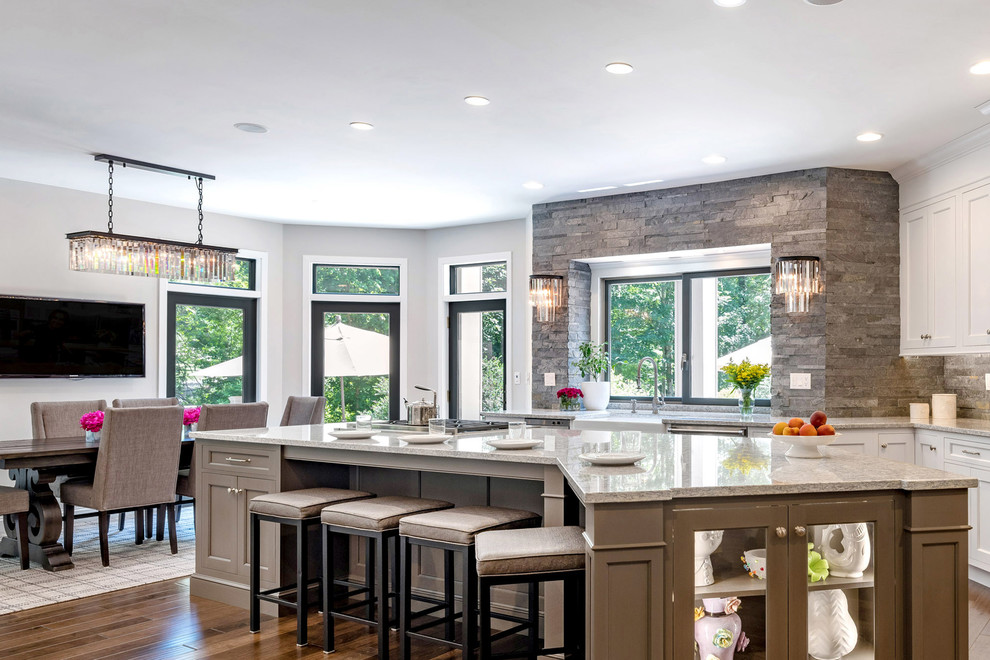 Inspiration for an expansive traditional eat-in kitchen in Bridgeport with a farmhouse sink, shaker cabinets, white cabinets, grey splashback, stone tile splashback, dark hardwood floors, with island and grey benchtop.