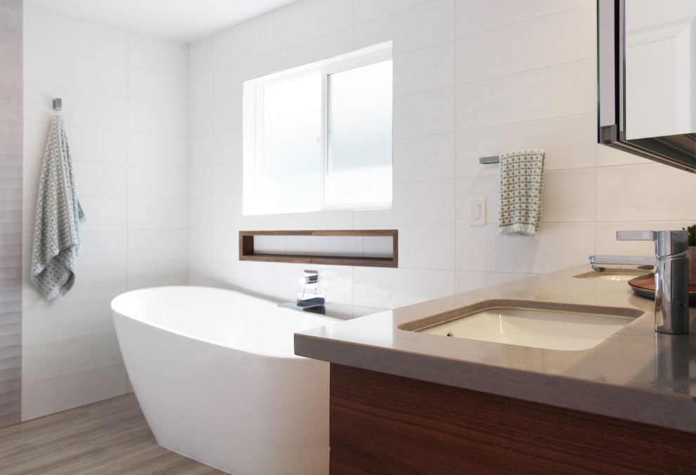 Large transitional master white tile and ceramic tile porcelain tile, gray floor and double-sink freestanding bathtub photo with flat-panel cabinets, dark wood cabinets, a one-piece toilet, white walls, an undermount sink, quartz countertops, gray countertops, a niche and a floating vanity