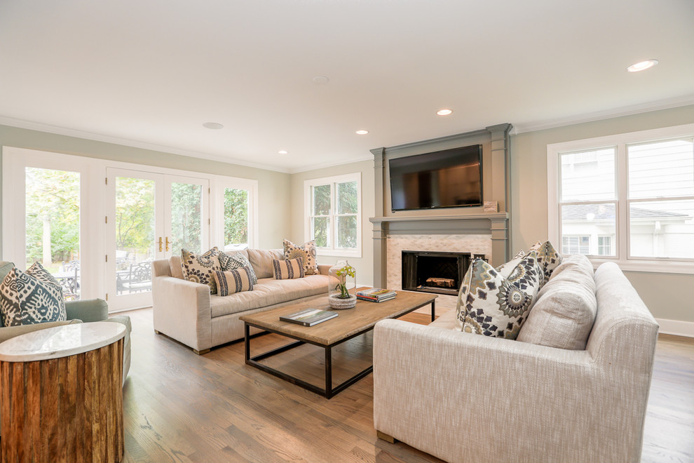 Photo of a mid-sized country open concept family room in Chicago with grey walls, medium hardwood floors, a standard fireplace, a tile fireplace surround and a wall-mounted tv.