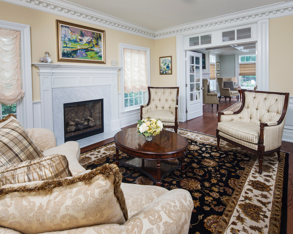 This is an example of a formal enclosed living room in New York with beige walls, medium hardwood floors, a standard fireplace, a stone fireplace surround and no tv.