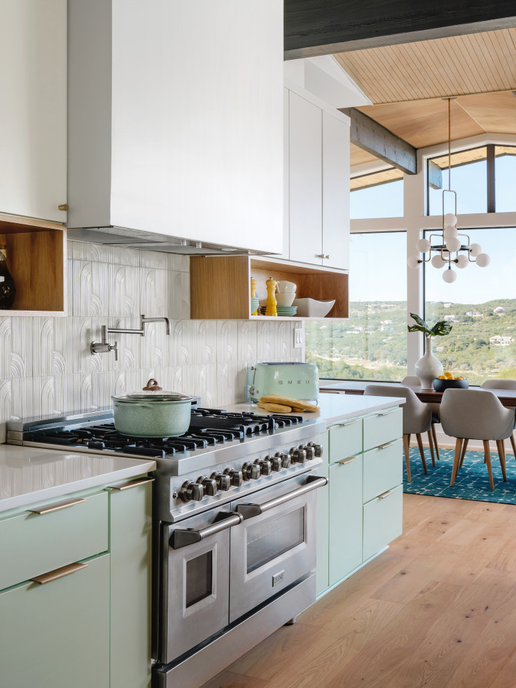 Inspiration for an expansive midcentury eat-in kitchen in Austin with a drop-in sink, flat-panel cabinets, turquoise cabinets, quartz benchtops, white splashback, porcelain splashback, stainless steel appliances, medium hardwood floors, with island, beige floor, white benchtop and wood.