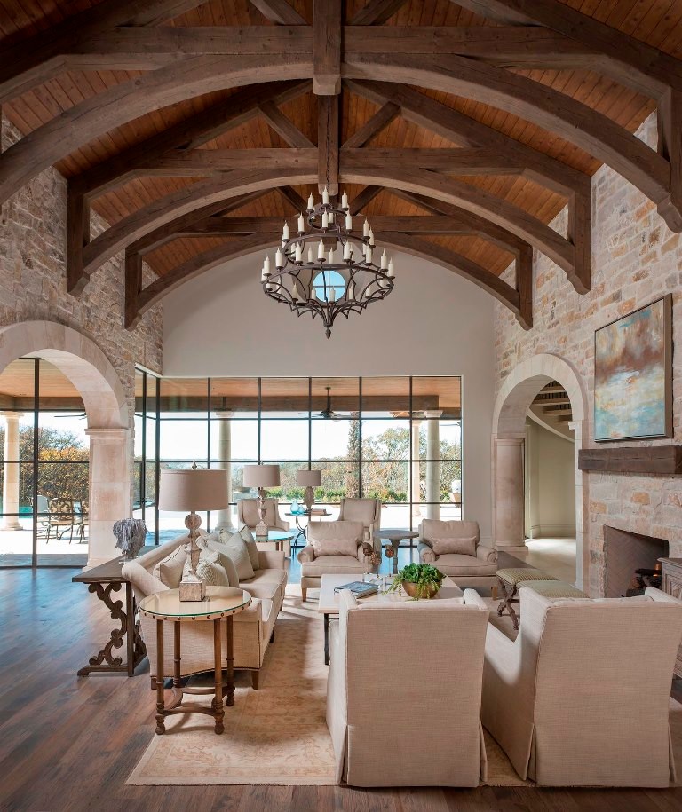 Inspiration for an expansive mediterranean open concept family room in Dallas with white walls, light hardwood floors, a standard fireplace, a stone fireplace surround and a wall-mounted tv.