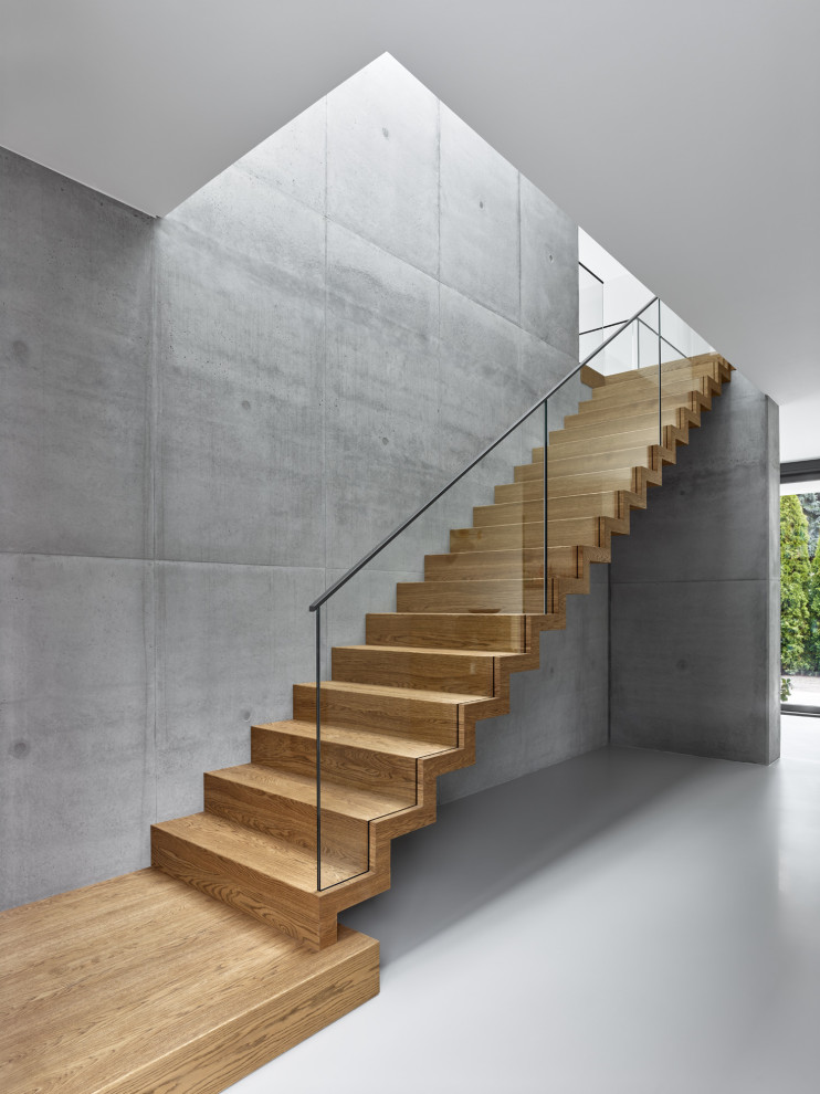 Photo of a mid-sized modern wood straight staircase in Berlin with wood risers and glass railing.