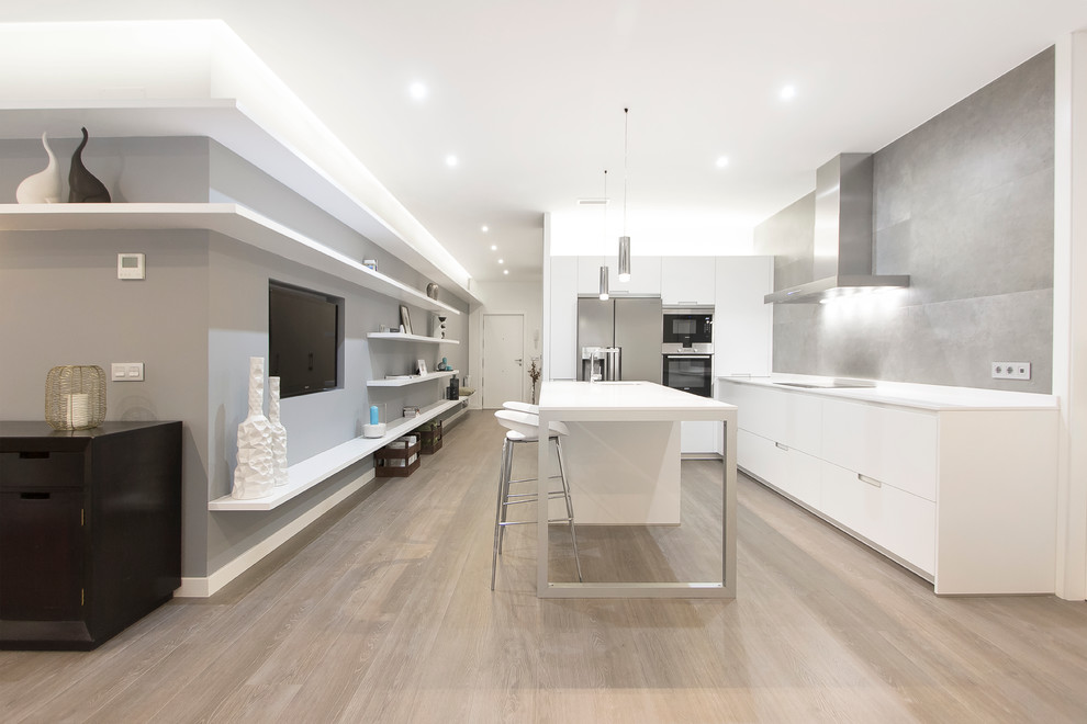 Design ideas for a mid-sized modern l-shaped open plan kitchen in Madrid with an integrated sink, flat-panel cabinets, white cabinets, quartz benchtops, grey splashback, cement tile splashback, stainless steel appliances, medium hardwood floors and with island.