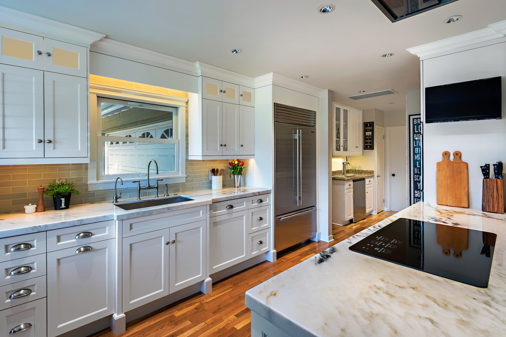 Mid-sized transitional single-wall medium tone wood floor enclosed kitchen photo in Phoenix with an undermount sink, shaker cabinets, white cabinets, marble countertops, gray backsplash, subway tile backsplash, stainless steel appliances and an island