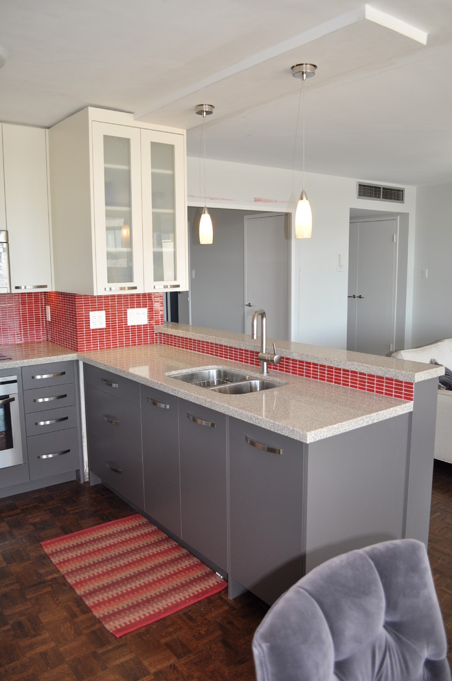 Small contemporary u-shaped open plan kitchen in Toronto with an undermount sink, flat-panel cabinets, grey cabinets, quartz benchtops, red splashback, glass tile splashback, stainless steel appliances, dark hardwood floors and a peninsula.