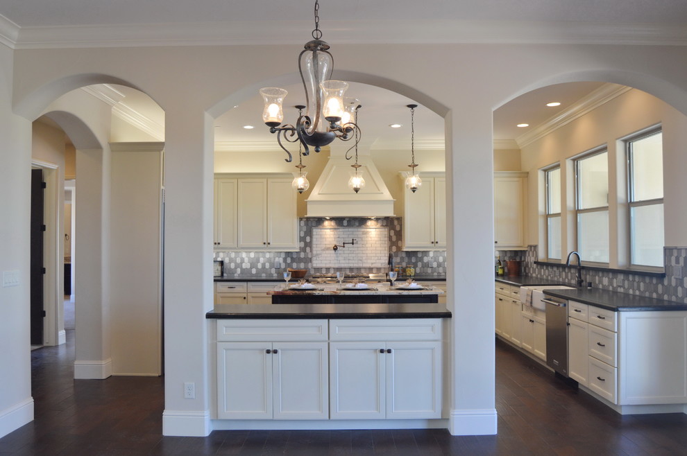 Mid-sized transitional u-shaped medium tone wood floor enclosed kitchen photo with a farmhouse sink, recessed-panel cabinets, white cabinets, solid surface countertops, gray backsplash, ceramic backsplash, stainless steel appliances and an island