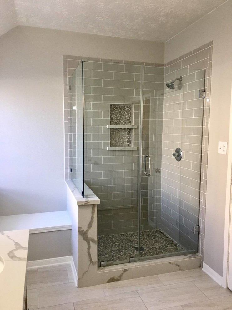 Design ideas for a contemporary master bathroom in Houston with shaker cabinets, grey cabinets, a corner shower, subway tile, grey walls, ceramic floors, wood benchtops, grey floor, a hinged shower door and grey benchtops.