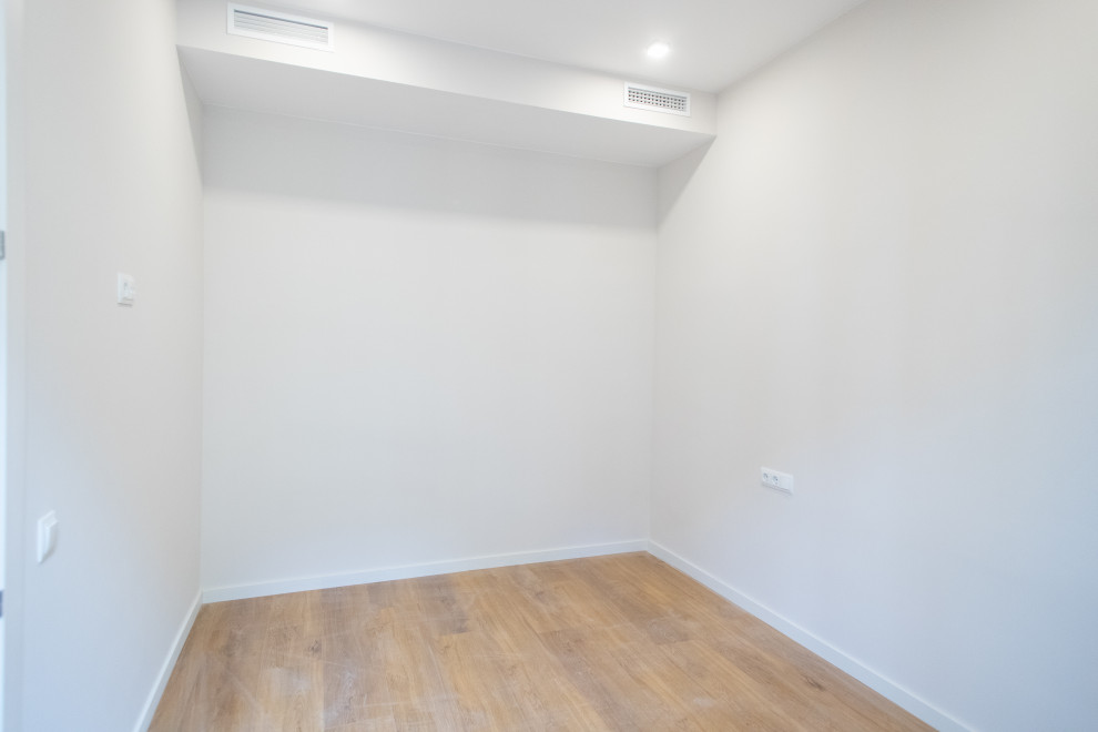 Immagine di una camera matrimoniale minimal di medie dimensioni con pareti beige, pavimento in legno massello medio, nessun camino e pavimento marrone