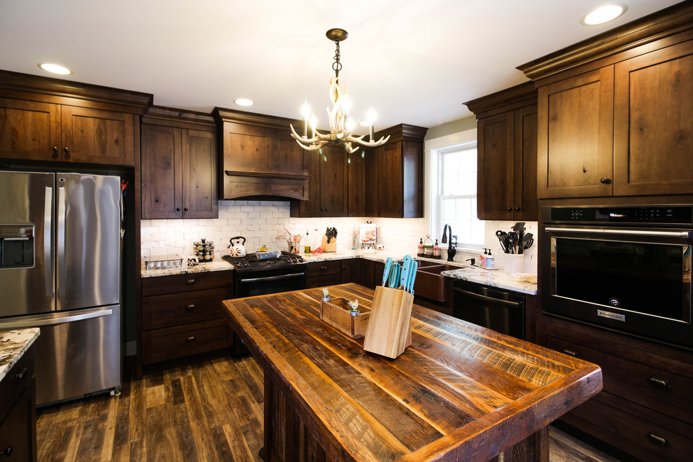 Inspiration for a mid-sized rustic l-shaped vinyl floor and brown floor enclosed kitchen remodel with a farmhouse sink, shaker cabinets, dark wood cabinets, granite countertops, white backsplash, ceramic backsplash, stainless steel appliances, an island and white countertops