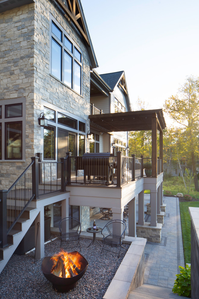 This is an example of a large traditional back first floor metal railing terrace in Milwaukee with a fire feature and a pergola.