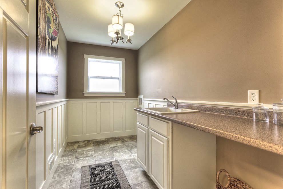 This is an example of a mid-sized arts and crafts galley dedicated laundry room in Detroit with a drop-in sink, white cabinets, laminate benchtops, beige walls, linoleum floors, a side-by-side washer and dryer and raised-panel cabinets.